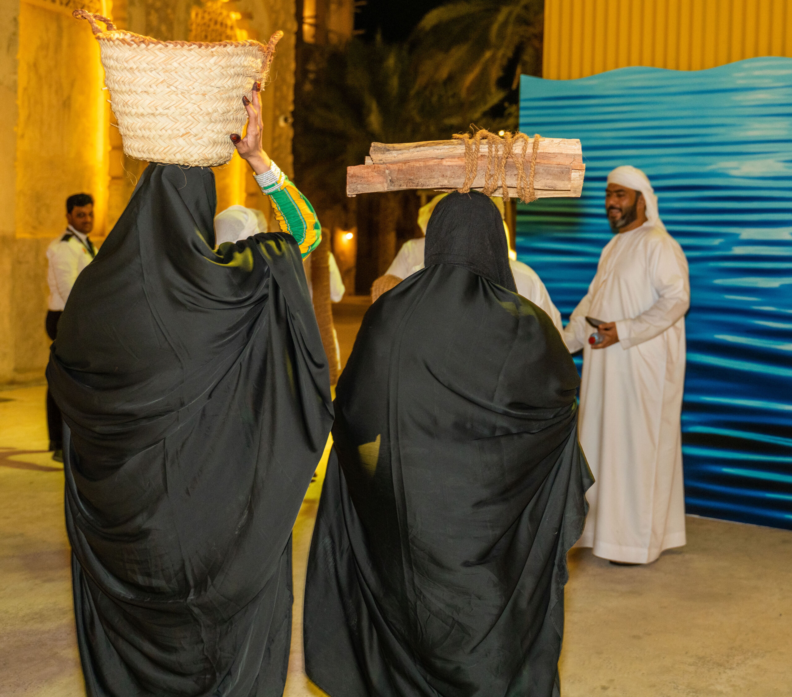 Image of two Emirati women carrying traditional baskets at a heritage site project managed by Talents UAE